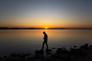 Homem andando em lago no por do sol