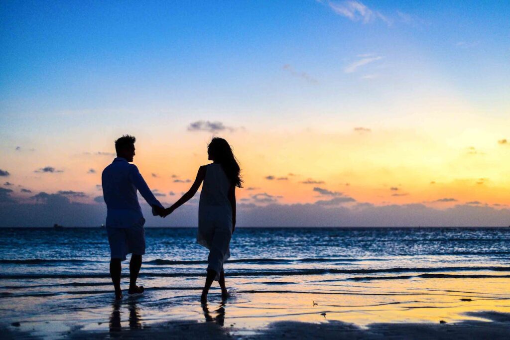 Como saber se fizeram macumba pro meu relacionamento: casal na praia ao por do sol.